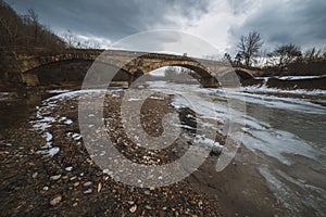 Old bridge over the river winter landscape