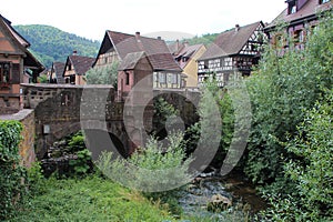 old bridge and weiss river in a village (kaysersberg) in alsace (france)