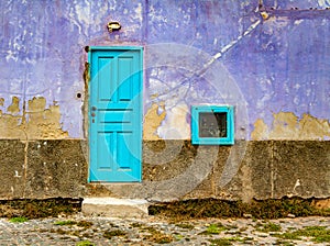 Old, bright violet wall with a blue door and window