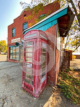 Old british english telephone phone box booth in front of a deserted hotel in a rundown ghost town