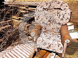 Old broken armchair at the dump with boards