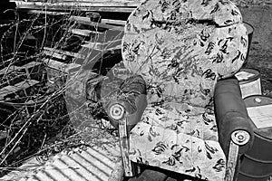 Old broken armchair at the dump with boards