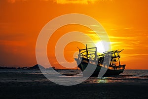 Old broken boat abandoned on the beach at sunset ,Red sky