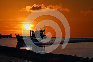 Old broken boat abandoned on the beach at sunset ,Red sky