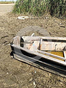 Old broken boat on the river bank near the reeds. Countryside. The dried river