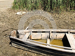 Old broken boat on the river bank near the reeds. Countryside. The dried river