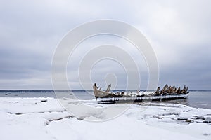 Old broken boat wreck and rocky beach in wintertime.