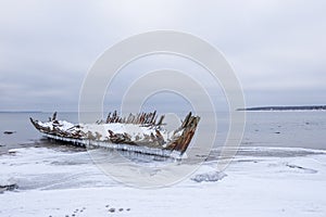 Old broken boat wreck and rocky beach in wintertime.
