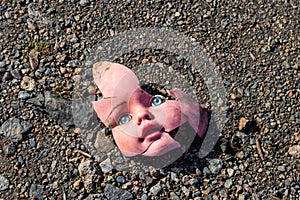 Old broken doll face on ground