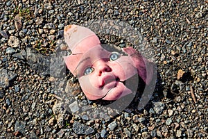 Old broken doll face on ground