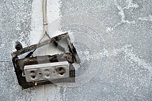 old broken electric socket on dirty cement wall