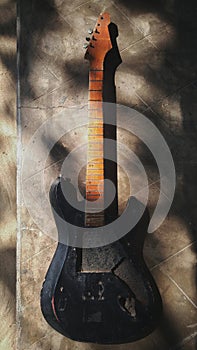 Old broken guitar in sunlight shadows