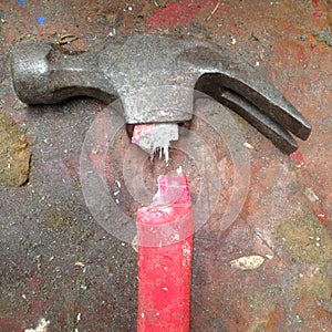 Old broken hammer with red fibreglass handle on a stained grungy