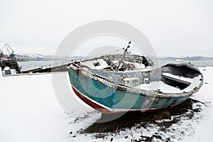 Old broken lifeboat lies on a pier in winter