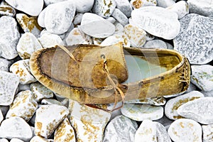 Old broken moccasin abandoned on white gravel