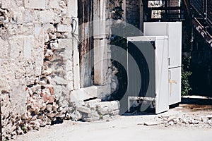 Old, broken refrigerators in the yard of an old ruined house.