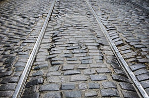 An old, broken road, made of granite stone with tram rails. Background stone.