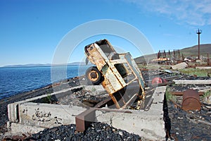 Old broken rusty abandoned car upside down at sea coast