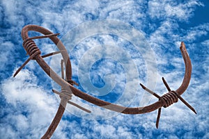 Old broken rusty barbed wire against the dramatic sky