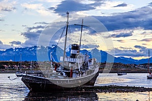 Old broken ship stranded ashore and village with mountains