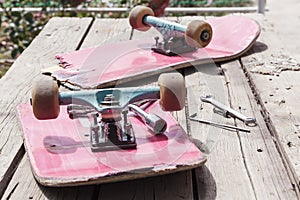 The old broken skateboard lies with a spanner on a wooden table in the open air