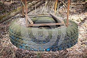 Old broken swing made of metal and car tire on abandoned playground among trees in ghost town Pripyat, Chernobyl Exclusion Zone,