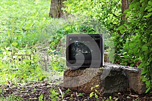 old broken television stands on a concrete pedestal in the city yard.