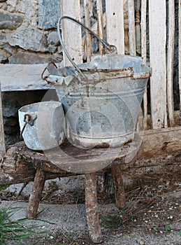 Broken tin bucket and an pot over the stool of the old stable