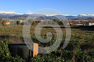 Old broken TV and view to snowy mountain range of Pindus, Epirus, Greece