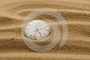 Old broken watch on a sand background