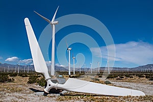 Old broken wind turbine blade in field of wind turbines