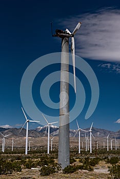 Old broken wind turbine in field of wind turbines