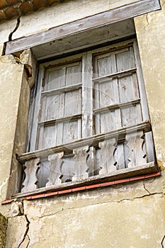 Old broken window of an abandoned house with wooden shutters