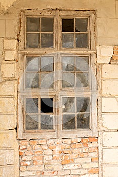 Old broken window with dust on a cracked brick wall