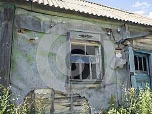 An old broken window of a house in the village with broken glass. Abandoned house. Countryside. sunny day