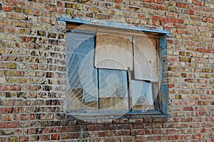 Old broken window with a lattice on a brick brown wall