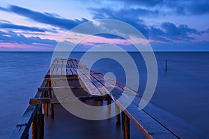 Old broken wooden bridge in the sea, long exposure, sunrise