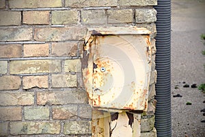 Old broken metal electricity box on brick wall