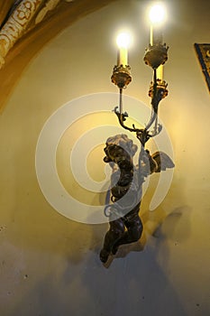 old bronze angel chandelier on the wall of the living room close-up. Interior design. Interior decor