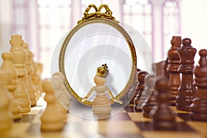 old, bronze crown on anthropomorphic white queen, pawn, oval mirror, figures on chessboard blackboard, concept supreme power,
