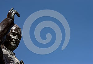 Old Bronze statue of a Saint with an hand up to the blue sky