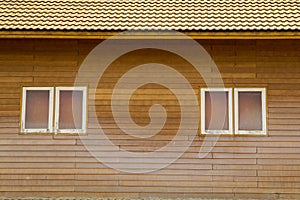 Old brown clay tiles roof pattern with small windows on wood wall