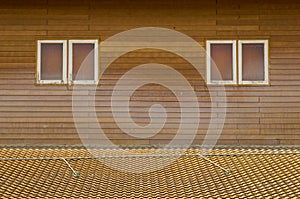 Old brown clay tiles roof pattern with small windows on wood wall