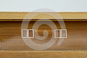 Old brown clay tiles roof pattern with small windows on wood wall