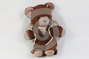 Old brown damaged teddy bear is sitting in the white studio