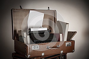 Old brown suitcases with old retro typing machine on white background