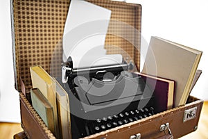 Old brown suitcases with old retro typing machine on white background