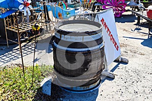 An old brown and white wood barrel next to a white and red antiques sign surrounded by various antiques in Douglasville