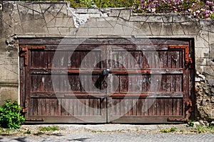 Old brown wooden gate with lock in a stone fence