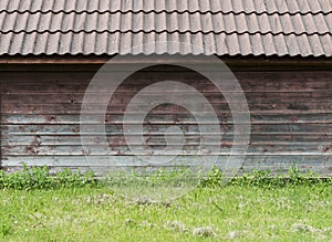 Old brown wooden wall with green grass as background